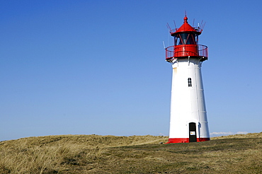 Lighthouse painted red a white standing on grassy hill, Ellenbogen, Sylt Island, North Frisian Islands, Schleswig-Holstein, Germany