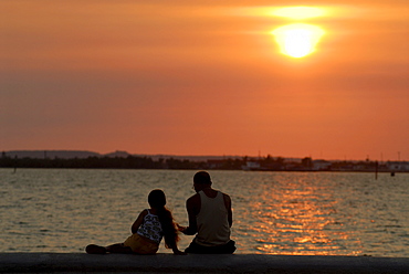 Man and child sitting on the malecon at sunset, Cienfuegos, Cuba, Americas