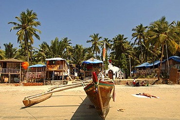 India, Goa, fishing boat and bamboo huts on Palolem Beach