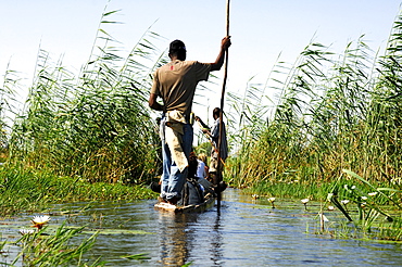 Locals in Mokoro dugoutboat on a tourist excursion in the Okavango Delta, Botswana