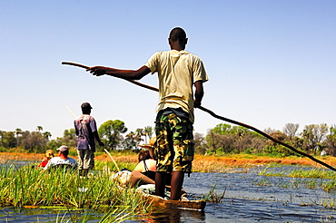 Locals in Mokoro dugoutboat on a tourist excursion in the Okavango Delta, Botswana