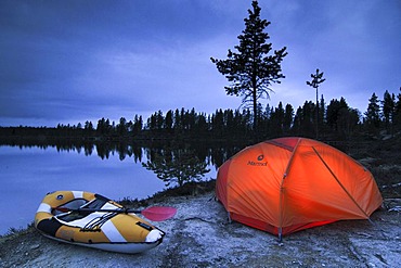 Illuminated tent and canoe at dawn, Femund, Femundsmarka national park, Norway