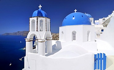 Blue and white domed church and bell tower in front of the blue sea, Oia, Ia, Santorini, Cyclades, Greece, Europe