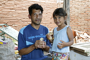 Guarani father and daughter with fledgling in his hand, in the poor area of Chacarita, Asuncion, Paraguay, South America