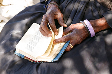 Elderly woman turning the pages of a hymnal, Sehitwa, Botswana, Africa