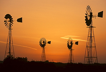 Wind driven water pumps silhouetted against evening sunset sky near Protaras, Cyprus