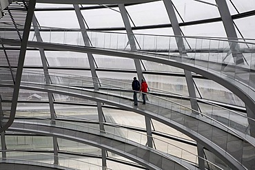 Couple walks hand in hand on a stairway in a huge modern cupola made of glass, Reichstag, Berlin Germany