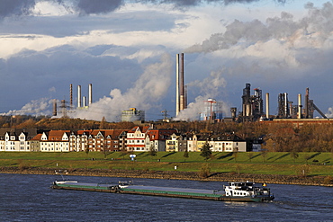 Row of houses on the bank of the river Rhine at Laar, in front of ThyssenKrupp steel works Meiderich/Beek, Duisburg, NRW, Germany