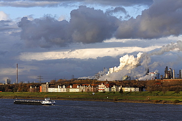 Row of houses on the bank of the river Rhine at Laar, in front of ThyssenKrupp steel works Meiderich/Beek, Duisburg, NRW, Germany