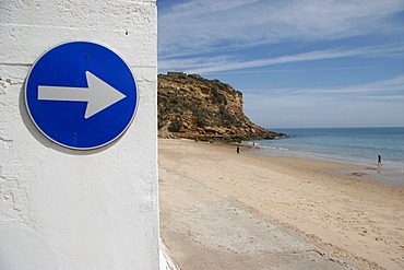 A street sign on a wall next to a beach in Salema, Algarve, Portugal