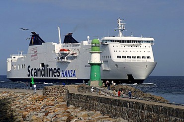 A big ferry ship by Scandlines shipping company passes a lighthouse at the port entrance of Warnemuende, Mecklenburg-Vorpommern, Germany