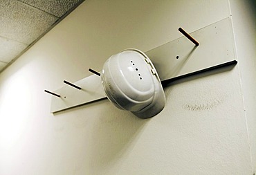 White hard hat on coat hook in front of white wall