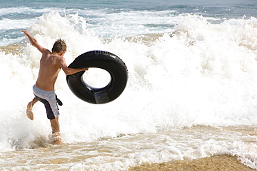 Teenager with floating tyre, Jandia, Fuerteventura, Canary Islands, Spain