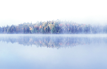 Early morning mist and autumn coloured trees on an island in Lac Bouchard Lake, La Mauricie National Park, Quebec, Eastern Canada