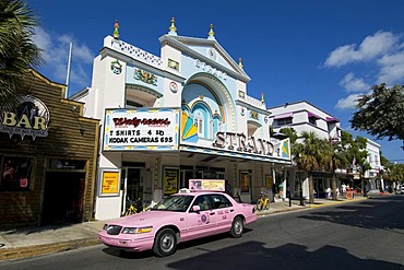 Pink cab driving past Strand's Department Store in Key West, Florida, USA