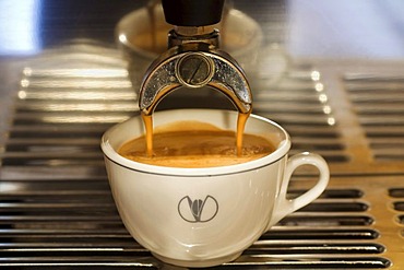 A cup of coffee is prepared with an espresso machine