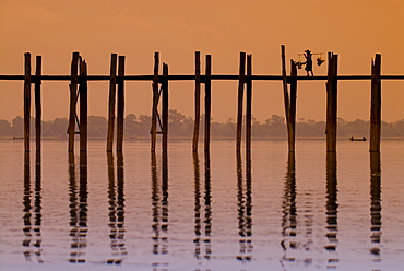 Man carrying a load crossing the U Bein Bridge at sunset, old wooden teak bridge, Mandalay, Myanmar, Southeast Asia