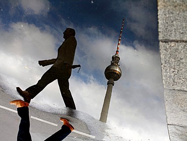 Pedestrian and telecommunications tower reflected in a puddle, Stuttgart, Baden-Wuerttemberg, Germany