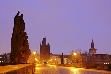 Two people walking over the Charles Bridge at dawn, Prague, Czech Republic