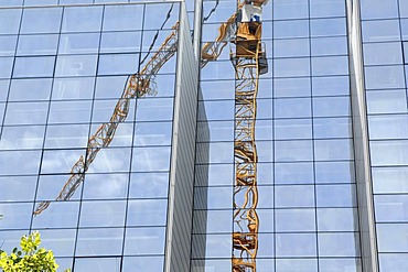 Reflection of a building crane in a modern glass facade