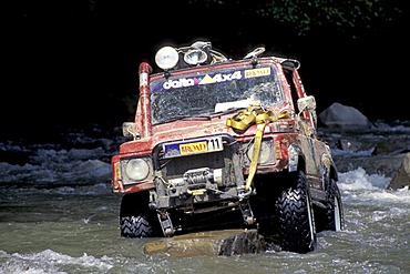 Offroad vehicle is standing on a rock in a river