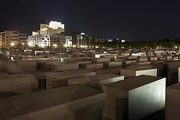 The lit Holocaust memorial at night with view of the multistoried buildings at the Potsdamer place, Berlin, Germany