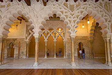 Tourists beneath the ornate stone carved arched passageway of the Santa Isabel Patio, Palacio de Aljaferia palace, Moorish architecture, Zaragoza, Saragossa, Aragon, Spain