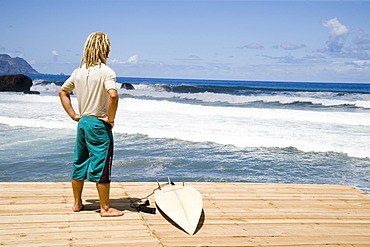 Young surfer in Sao Vincente, Madeira, Portugal waiting for tides looking into the ocean