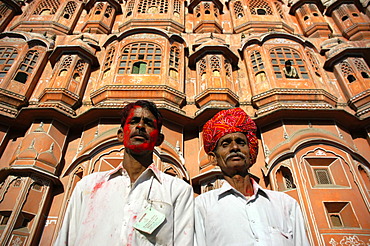 Indian men with turban and red colour in the face are standing in front of palace of the winds Jaipur Holi Festival Rajasthan India