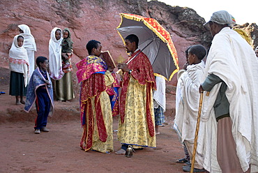 Ethiopian Orthodox Christianity priest reads out of the holy bible with believers in front of the rock hewn church Beta Marqorewos Lalibela Ethiopia