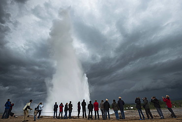 Tourists watching a steam and water column, Stokkur geyser against the light, Haukadalur Valley, Golden Circle, Suâˆšâˆžurland, South Iceland, Iceland, Europe