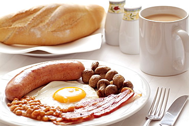 Traditional English Fried Breakfast of Sausage, Egg, Bacon, Mushrooms and Beans. Served with a Mug of Tea.