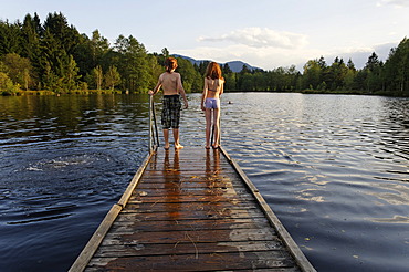 Boy and girl on a jetty, Unterbuchner Weiher, small swimming lake, near Bad Heilbrunn, Upper Bavaria, Bavaria, Germany, Europe