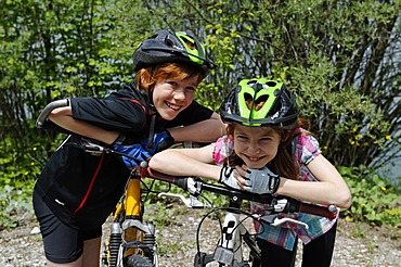 Two children, boy and girl with mountain bikes and helmets