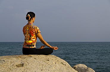 Woman in a yoga position, Padmasana, by the sea in Kanyakumari, Tamil Nadu, India, Asia