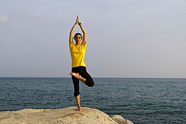 Woman in a yoga position, Vrikshasana, by the sea in Kanyakumari, Tamil Nadu, India, Asia