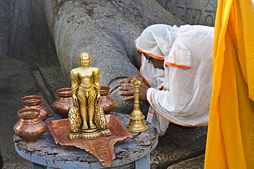 Jain pilgrim is praying at the feet of the gigantic statue of Gomateshwara in Sravanabelagola, Karnataka, India, Asia