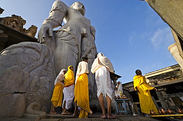 Jain pilgrims are reciting religious texts at the feet of the gigantic statue of Gomateshwara in Sravanabelagola, Karnataka, India, Asia