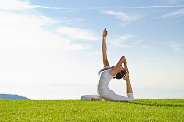 Young woman practising Hatha yoga outdoors, showing the pose kapotasana, dove pose, pigeon pose, Nove Mesto, Okres Teplice, Czech Republic, Europe