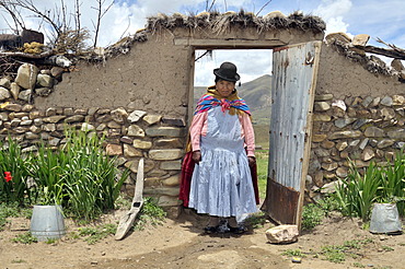 Portrait of a woman in traditional dress of the Quechua in a yard gate, Bolivian Altiplano highlands, Departamento Oruro, Bolivia, South America