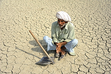 Farmer sitting on dried loamy soil, Basti Lehar Walla village, Punjab, Pakistan, Asia