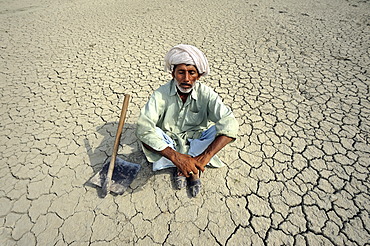 Farmer with closed eyes sitting on dried loamy soil, dreaming, Basti Lehar Walla village, Punjab, Pakistan, Asia