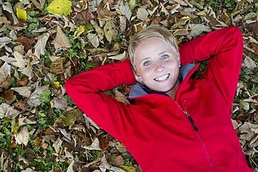 Young woman lying on autumn leaves