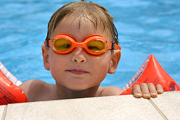 Boy in the water with diving goggles and water wings