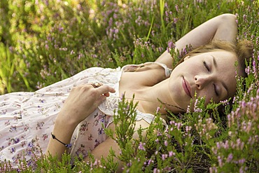 Young woman lying on a heather carpet