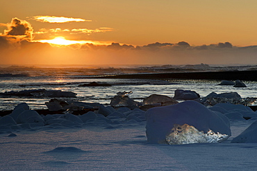Sunset behind the snow-covered icebergs at the Atlantic coast near Joekulsarlon, Vatnajoekull National Park, Iceland, Europe
