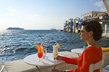 Woman enjoying a cocktail and a view over the sea, Little Venice, Mykonos Town, Mykonos, Cyclades, Greece