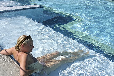 Young woman leaning against the side of a swimming pool