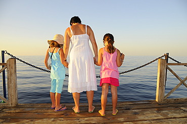 Mother with two children looking at the sea