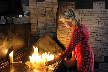 Woman lighting a candle in the Stone Gate (Kamenita vrata), a place of prayer for believers, Zagreb, Croatia